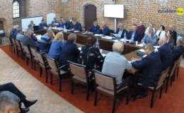 Na zdjęciu widać radnych i osoby uczestniczące w sesji rady miasta, sesja odbywa się w sali zamkowej uczestnicy siedzą za stołem