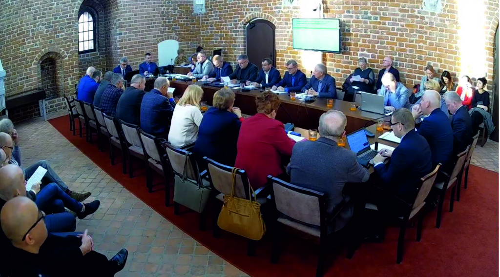 widać radnych i osoby uczestniczące w sesji rady miasta, sesja odbywa się w sali zamkowej, uczestnicy siedzą za stołem