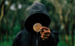 postać w kapturze trzyma bitcoin