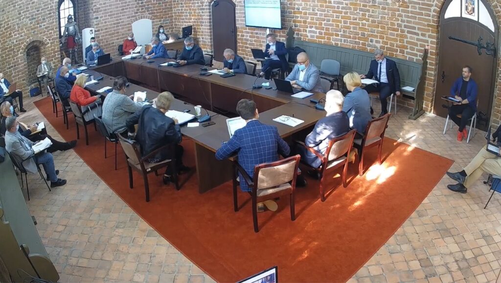 widać radnych i osoby uczestniczące w sesji rady miasta, sesja odbywa się w sali zamkowej, uczestnicy siedzą za stołem