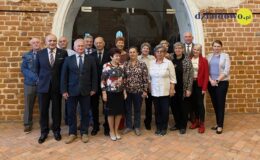 Na zdjęciu grupa osób, kobiety i mężczyźni, stoją w sali zamkowej