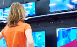 osoba przygląda się telewizorom stojącym na półkach