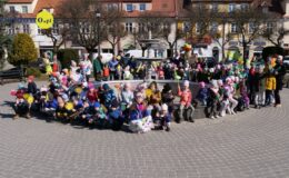 dzieci i dorośli stoją i siedzą przy nieczynnej fontannie