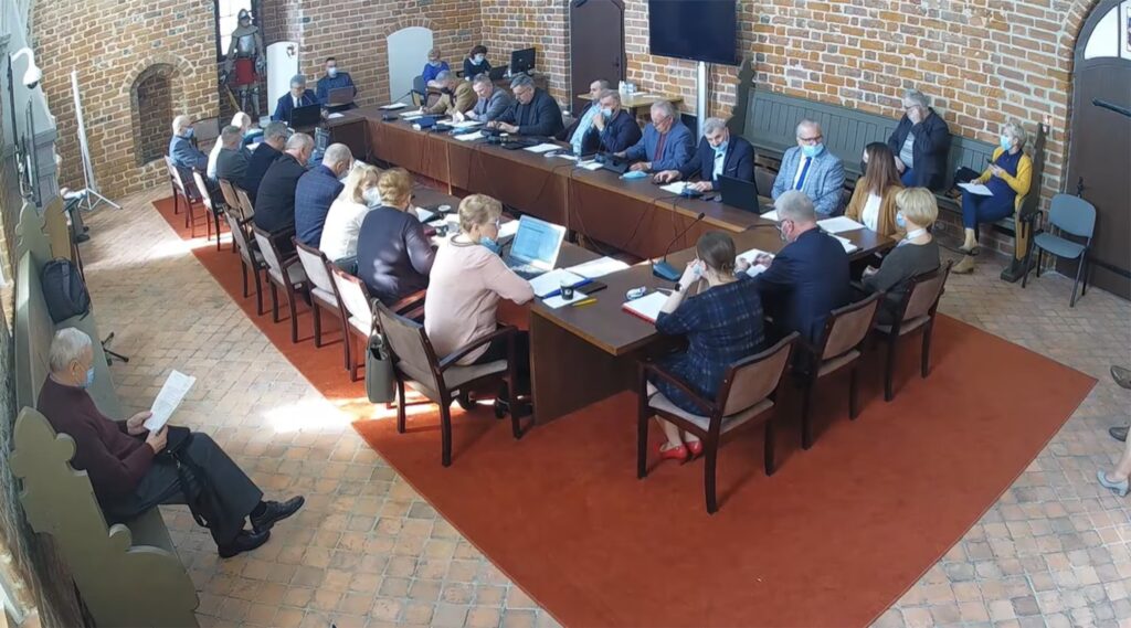 Na zdjęciu widać radnych i osoby uczestniczące w sesji rady miasta, sesja odbywa się w sali zamkowej uczestnicy siedzą za stołem