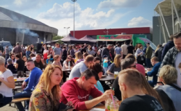 (na zdjęciu widać kilkadziesiąt osób siedzących przy stolikach, na świeżym powietrzu)