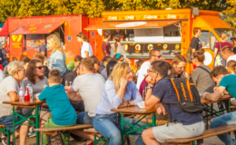 siedzi grupa osób za stolikami, Festiwal Smaków Food Trucków zagości