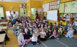 dzieci siedzące na podłodze w klasie i oglądają przedstawienie