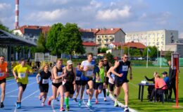 grupa zawodników biegnących po bieżni na stadionie