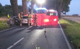 czerwony parawan na drodze, przy nim strażacy, policja i karetka pogotowia na miejscu śmiertelnego wypadku