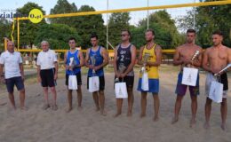 stoi grupa mężczyzn na boisku do piłki plażowej – zawodnicy i sędziowie