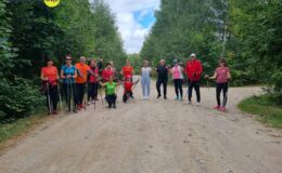 grupa osób uczestnicząca w treningu Nordic Walking na drodze w lesie