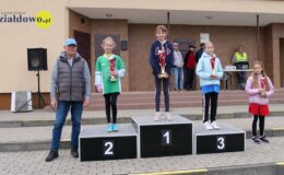 stoi grupa osób, dzieci w rękach trzymają puchary