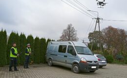 policjanci obsługujący drona na zewnątrz przy nich policyjny nieoznakowany bus i oznakowany radiowóz, w powietrzu unosi się dron / Fot. policja