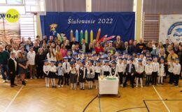 stoi grupa dzieci i dorosłych w sali gimnastycznej
