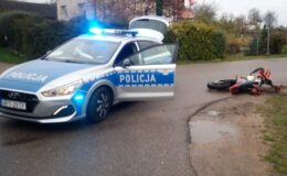 na drodze stoi radiowóz policyjny i przewrócony motocykl