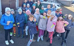 dzieci z wychowawcą, policjantem i policjantką na placu na tle radiowozu policyjnego