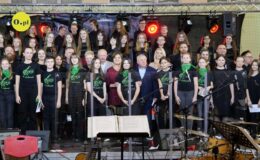 na scenie stoi grupa osób, dzieci, młodzież dorośli, uczestnicy koncertu