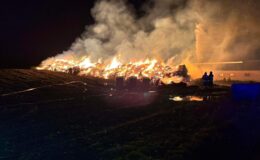 widać płonący stóg słomy, 2 strażaków gasi pożar