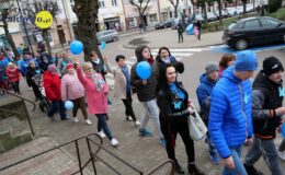 ulicą Działdowa, idzie grupa osób: dzieci, dorośli w Marszu dla Autyzmu