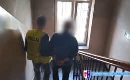 widoczny jest zatrzymany mężczyzna prowadzony po schodach w dół przez policjanta