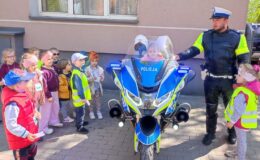Policjant ruchu drogowego i dziewczynka na motocyklu policyjnym w otoczeniu dzieci
