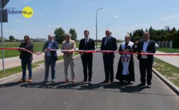 na drodze stoją mężczyźni podczas uroczystego przecinania wstęgi nad drogą