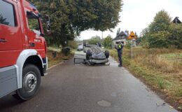 miejsce zdarzenia drogowego, widać samochód leżący na dachu, wóz strażacki i policjanta /fot. KPP Działdowo