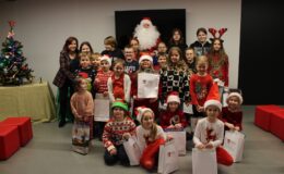 grupa uczestników Mikołajkowych Warsztatów w Muzeum wraz z panią z Muzeum i Mikołajem