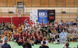 pamiątkowa fotografia zawodników, trenerów i gości, osoby stoją i siedzą w hali sportowej