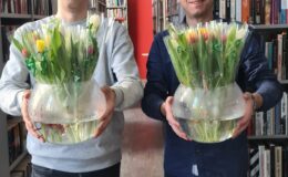 panowie Piotr Kozikowski i Piotr Herman pozują z kwiatkami czekając w bibliotece na Panie
