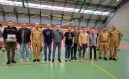 stoi grupa mężczyzn w sali gimnastycznej SP 2