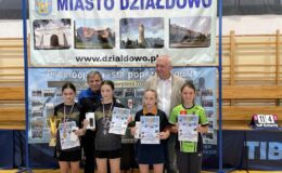 stoi w hali sportowej grupa dzieci i dwie osoby dorosłe