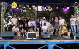 grupa osób na scenie pozuje do pamiątkowej fotografii – uczestnicy Zlotu Pojazdów Zabytkowych, kobiety i mężczyźni