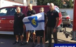 stoi czterech mężczyzn, trzymają flagę z herbem Lidzbarka / fot. policja