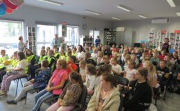 grupa dzieci siedzi na krzesełkach w sali miejskiej biblioteki w Działdowie