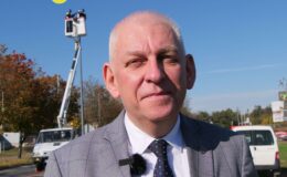 burmistrz Grzegorz Mrowiński na tle latarni miejskich, których oprawy podlegają wymianie, widać podnośnik i pracowników