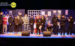 na scenie stoi grupa osób: kobiety i mężczyźni