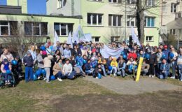 grupa osób: dzieci i dorośli pozują do pamiątkowej fotografii tuż przed Marszem dla Autyzmu