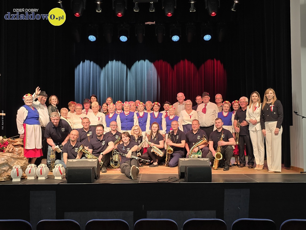 „Ojczyzna w sercu, pieśni na ustach”. Wzruszający koncert patriotyczny seniorów pamiątkowe zdjęcia osób dorosłych i młodzieży, stojących na scenie MDK w Działdowie