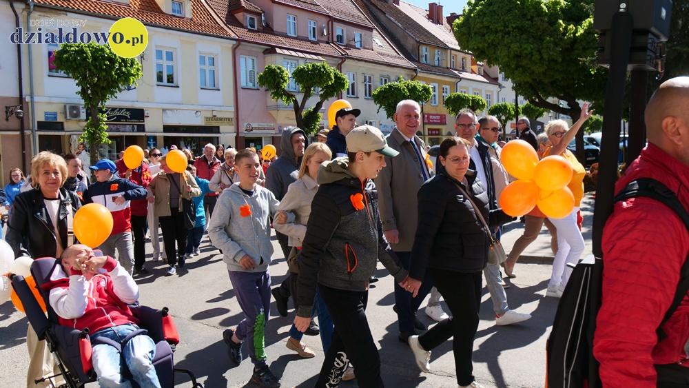 Marsz Godności osób niepełnosprawnych i piknik integracyjny widać osoby idące ulicami w Marszu Godności w Działdowie