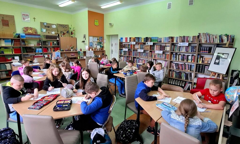 A tak wyglądał Tydzień Bibliotek w Szkole Podstawowej nr 2 dzieci i młodzież siedzą przy stolikach w bibliotece Szkoły Podstawowej nr 2 w Działdowie