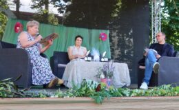 siedzą trzy osoby na scenie w Parku HDK w Działdowie podczas pierwszej edycji Powiatowych Wieczorów z Poezją i Prozą