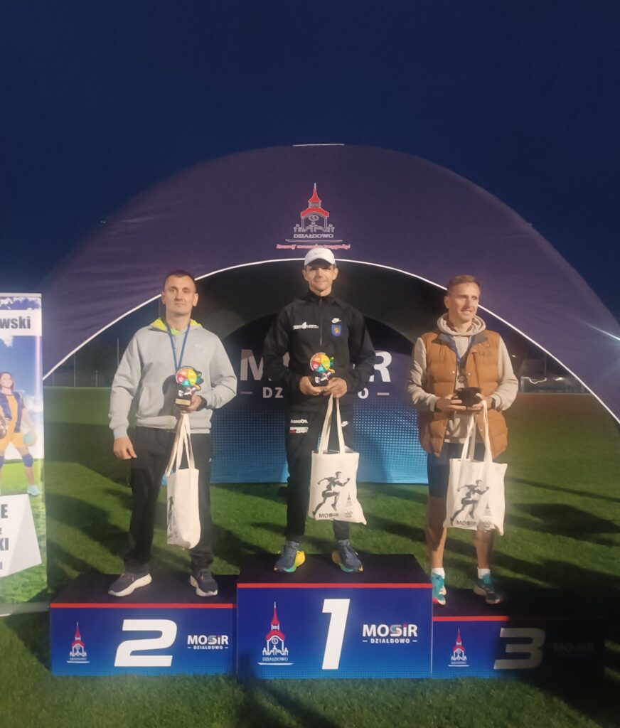 na podium stroją zwycięzcy biegu mężczyzn z kategorii Open, trzymają nagrody i statuetki