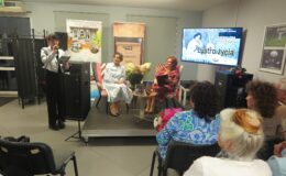 jedna osoba czyta przy mikrofonie, a dwie osoby siedzą