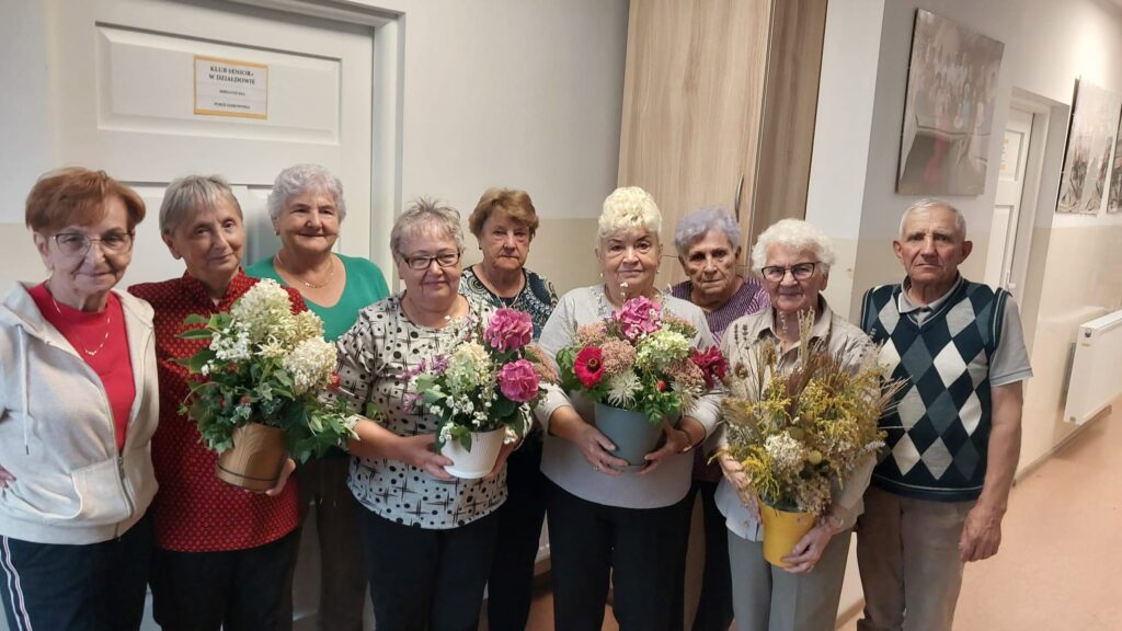 pamiątkowa fotografia seniorów ich własnoręcznie wykonanych jesiennych kompozycji