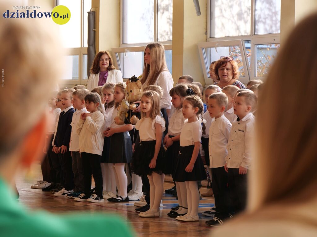 stoi grupa dzieci i nauczycieli, w sali gimnastycznej Szkoły Podstawowej nr 3 w Działdowie