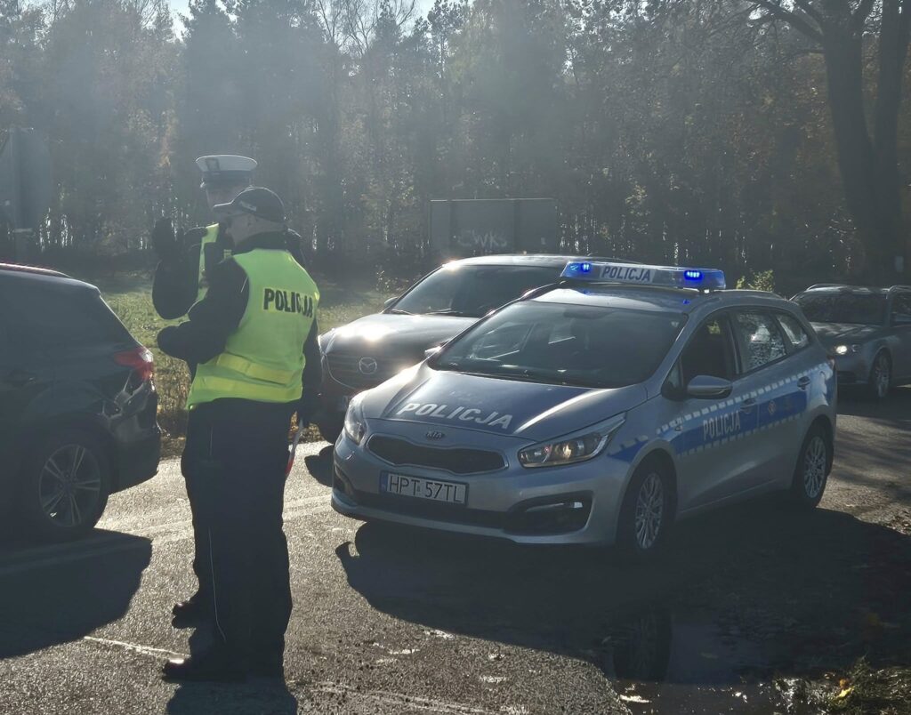 Podsumowanie akcji "Znicz 2025" widać stojących dwóch policjantów na drodze, radiowóz i samochody /fot. policja