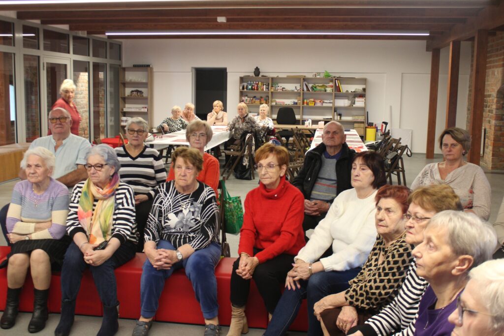 Seniorzy na warsztatach z okazji Narodowego Święta Niepodległości pamiątkowa fotografia seniorów wraz z panami opiekunkami