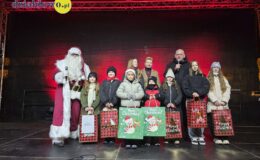 burmistrz, osoby dorosłe, dzieci i młodzież stoją na scenie, podczas ogłoszenia wyników konkursu na "Świąteczną Kartkę Bożonarodzeniową"