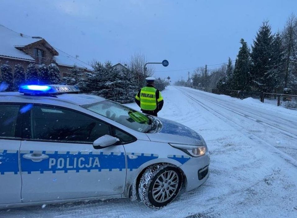 policjant, radiowóz i zaśnieżona droga / fot. policja